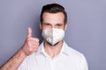 Close-up portrait of his he attractive healthy guy wearing safety n95 respirator mask showing thumbup stop influenza