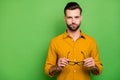 Close-up portrait of his he nice attractive serious bearded brown-haired guy in casual formal shirt holding in hands