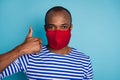 Close-up portrait of his he nice healthy guy wearing red cotton textile reusable safety mask showing thumbup stop mers
