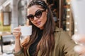 Close-up portrait of hispanic young woman with ribbon enjoying coffee in autumn day. Outdoor photo of cute tanned girl Royalty Free Stock Photo