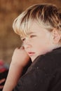 Close up portrait image of young blonde boy with blue eyes. Farm kid in moment of reflection