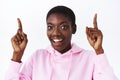 Close-up portrait of imressed pretty african-american woman with short hair, pointing fingers up and smiling camera with Royalty Free Stock Photo