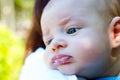 Cute little baby resting head on mother shoulder, beautiful child face with blue green eyes, close up portrait of infant burping Royalty Free Stock Photo