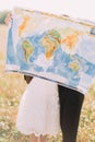 The close-up portrait of the just married holding the world map closing their faces at the background of the sunny field Royalty Free Stock Photo