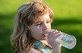 Close up portrait of kid boy drinking water from pet bottle outdoor. Royalty Free Stock Photo