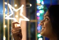 Close up portrait of a lady smiling and holding neon star light with bokeh background. Selective focus on face. Diwali