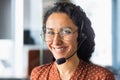 Close up portrait of latin american woman inside modern office with headset for video call, woman smiling and looking at Royalty Free Stock Photo