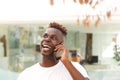 Close up laughing african young man talking on mobile phone and looking away Royalty Free Stock Photo