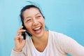 Laughing asian woman talking on cell phone against blue wall Royalty Free Stock Photo