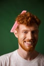 Close-up portrait of laughs young readhead man with pink hairbrush stuck in his hair