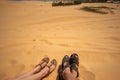 Close up portrait of legs,  legs of couples lying with a mixture of golden sand dunes.Feet of a man and a woman in sandals on the Royalty Free Stock Photo