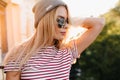 Close-up portrait of lightly-tanned blonde girl in trendy shining sunglasses. Outdoor photo of inspired fair-haired