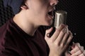 Close-up portrait lips emotional singing the young guy standing in front of the microphone stand holding his hands.