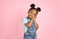 Close up portrait of little adorable African child girl in jeans overalls, having fun and looking at camera over pink Royalty Free Stock Photo