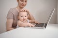 Close up portrait little baby boy funny facial expression sitting on mother`s lap studying laptop. Young mom work from home with Royalty Free Stock Photo