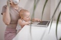 Close up portrait little baby boy funny facial expression sitting on mother`s lap studying laptop. Young mom work from home with Royalty Free Stock Photo