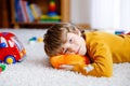 Close-up portrait of little blond kid boy playing at home with toys. Happy smiling child in casual clothes Royalty Free Stock Photo