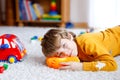 Close-up portrait of little blond kid boy playing at home with toys. Happy smiling child in casual clothes Royalty Free Stock Photo