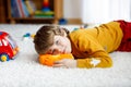 Close-up portrait of little blond kid boy playing at home with toys. Happy smiling child in casual clothes Royalty Free Stock Photo