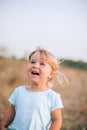 Close up portrait of little blonde girl with blue eyes outside with tousled hair and smiling face. Childhood in the country Royalty Free Stock Photo