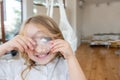 Close-up portrait of little blonde girl holding bright crystal magnifying glass to eye Royalty Free Stock Photo