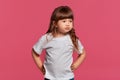 Close-up portrait of a little brunette girl dressed in a white t-shirt posing against a pink studio background. Sincere Royalty Free Stock Photo