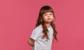 Close-up portrait of a little brunette girl dressed in a white t-shirt posing against a pink studio background. Sincere Royalty Free Stock Photo