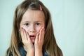 Close-up portrait of little child girl with long hair covering her mouth with hands Royalty Free Stock Photo