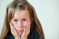 Close-up portrait of little child girl with long hair covering her mouth with hands Royalty Free Stock Photo