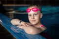 Close-up portrait little cute adorable blond caucasian kid girl in sport pink swimsuit and swimming goggles in clear Royalty Free Stock Photo