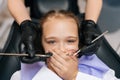 Close-up portrait of little cute child girl closing mouth by fear in dental clinic, frightened by dental drill, afraid Royalty Free Stock Photo