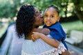 Close up portrait of little cute smiling African child girl in blue dress, looking at camera, while hugging pretty Royalty Free Stock Photo