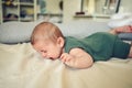 Close up portrait of little funny cute blonde infant boy child toddler with blue eyes in green linen bodysuit crying Royalty Free Stock Photo