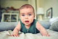 Close up portrait of little funny cute blonde infant boy child toddler with blue eyes in green linen bodysuit crying Royalty Free Stock Photo