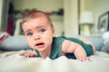 Close up portrait of little funny cute blonde infant boy child toddler with blue eyes in green linen bodysuit crying Royalty Free Stock Photo