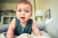 Close up portrait of little funny cute blonde infant boy child toddler with blue eyes in green linen bodysuit crying Royalty Free Stock Photo