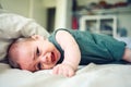 Close up portrait of little funny cute blonde infant boy child toddler with blue eyes in green linen bodysuit crying Royalty Free Stock Photo