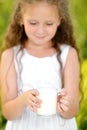 Close up portrait little girl holding glass of milk outdoor summer Royalty Free Stock Photo