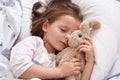 Close up portrait of little girl hugging her teddy bear and being happy, having rest after interesting day in kinder garten. Royalty Free Stock Photo
