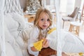 Close-up portrait of little girl riding on swing on macrame chair at home. Child is fooling around