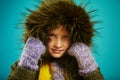 Close up portrait of little girl in warm autumn jacket with fur hood in green and mittens, shot on blue Royalty Free Stock Photo