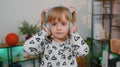 Happy child girl kid in headphones dancing and jumping while listening to the music at home alone Royalty Free Stock Photo