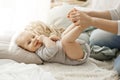 Close up portrait of little newborn son lying on bed, looking at camera while playing with mother. Kid smiling and put Royalty Free Stock Photo