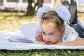 Close-up portrait of a little schoolgirl doing homework while lying on a blanket in a sunny autumn park. Outdoor education for Royalty Free Stock Photo