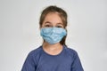 Close up portrait of little sportive girl child in sportswear wearing medical mask while standing isolated over white Royalty Free Stock Photo