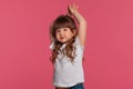 Close-up portrait of a little brunette girl dressed in a white t-shirt posing against a pink studio background. Sincere Royalty Free Stock Photo