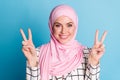 Close-up portrait of lovely cheerful glad muslimah girl showing double v-sign isolated over shine blue color background Royalty Free Stock Photo