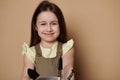 Close-up portrait lovely little girl in casual clothes, smiles looking at camera, holding garden tools, cream background Royalty Free Stock Photo
