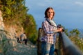 Close up portrait of lovely middle aged woman with dslr photo camera. Attractive thoughtful mature woman leaning resting