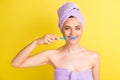 Close-up portrait of lovely naked girl wearing turban cleansing teeth isolated over vibrant yellow color background